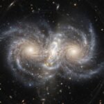 Galaxy collision unveils a dark matter mystery Two giant galaxies colliding in deep space revealing the separation of invisible dark matter mass.